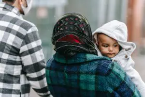 Woman carrying an infant with a man also in picture.