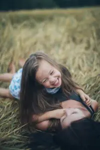 A mother and young daughter in a field laughing having a good time