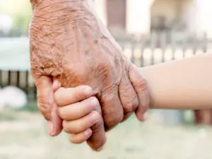 An aged hand holding a small childs hand.