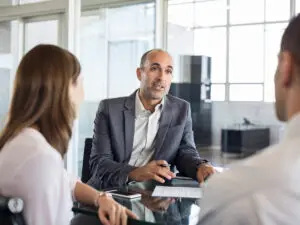 A lawyer meeting with a couple across a glass office table.