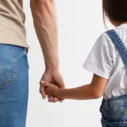 Trust And Support Concept. Cropped close up of man and girl holding hands, enjoying spending free time together, isolated over white studio background. Love And Family Care