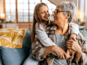 A grandmother with her granddaughter hugging her around her shoulders.