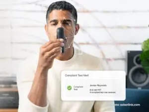 A person is using a Soberlink at-home breathalyzer that combines with facial recognition technology
