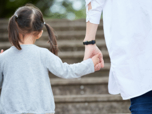 A small girl in pigtails holding hands with her mother.