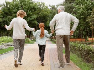 Two grandparents walking with their granddaughter from the back