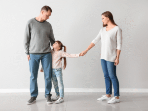 A young child holding hands with both parents who stand apart, visually representing how to help your child through a divorce with support and co-parenting.