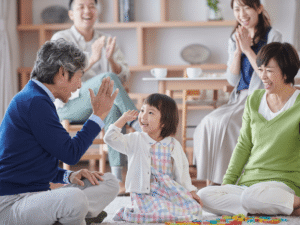 A smiling grandfather giving a high-five to a young grandchild during a family gathering, illustrating the relationship at the core of stepparent adoption and grandparent rights issues.