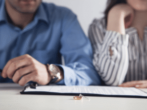 A pair of wedding rings placed on top of divorce papers, representing the difficult conversation of how to tell your spouse you want a divorce.