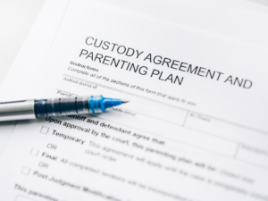 Close-up of a child custody agreement and parenting plan document with a pen, symbolizing legal modifications to child support and the process of adjusting financial obligations after a job loss or income change.