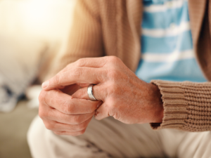 Close-up of an older adult’s hands removing a wedding ring, symbolizing divorce later in life and the emotional and financial considerations of spousal support in gray divorce cases.