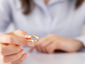 Close-up of a person holding a gold wedding ring, symbolizing marriage, separation, and the legal decisions involved in divorce.