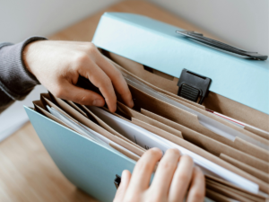 Hands organizing documents in a file organizer, representing the importance of maintaining accurate records and evidence in a high-conflict San Diego child custody case.
